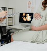Doctor making conclusion after ultrasound Close-up of doctor making notes in medical card after ultrasound exam of pregnant woman at hospital