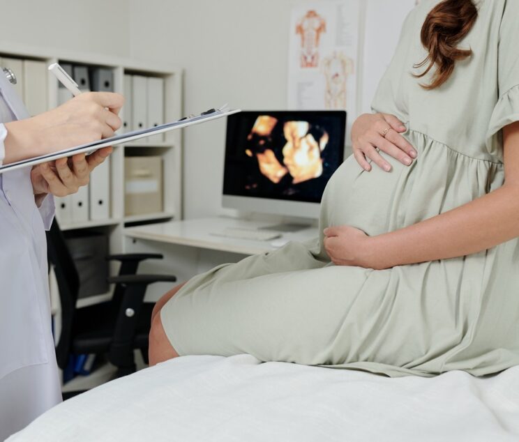 Doctor making conclusion after ultrasound Close-up of doctor making notes in medical card after ultrasound exam of pregnant woman at hospital